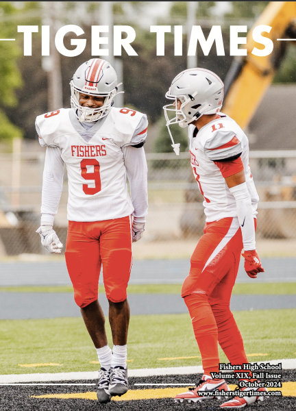 Two FHS football players next to each other on the field, with one celebrating.